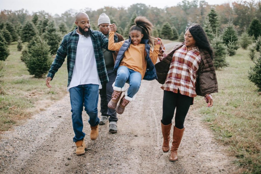 man and woman couple playfully swinging their daughter child